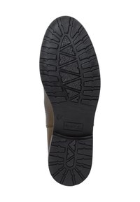 Semelle en caoutchouc noir avec un motif texturé de rainures et de crêtes angulaires. La vue de côté révèle un matériau supérieur marron, cousu au niveau de la couture.