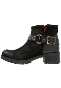 Black ankle boot with a suede upper, thick rubber sole, and a chunky heel. Features a wide strap with gold studs and a side zipper.