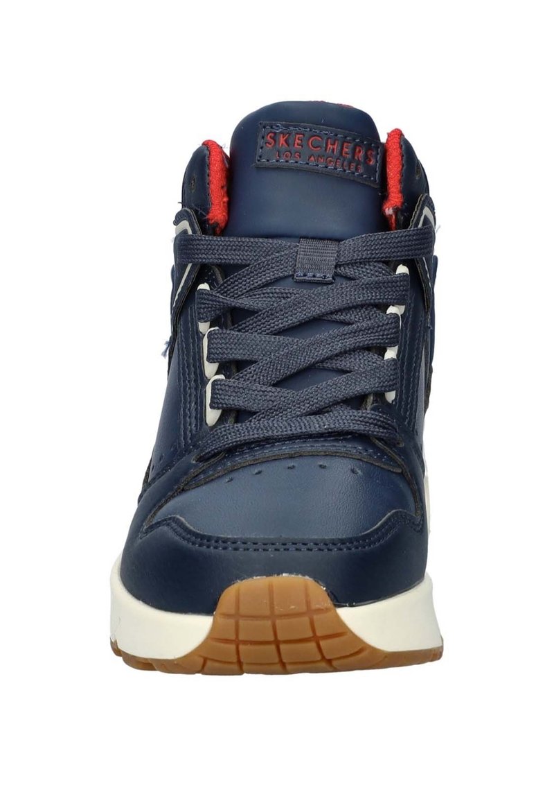 Sneaker atletica blu navy con tomaia in pelle, suola intermedia bianca, accenti rossi e suola esterna in gomma testurizzata. Presenta un collare imbottito e lacci.