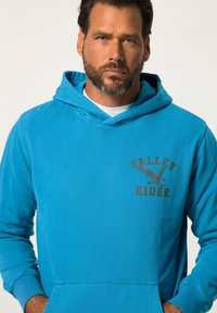 Felpa azzurra chiara in cotone, con tasca a marsupio frontale, grafica di un'aquila e la scritta "VALLEY RIDER" stampata in marrone.