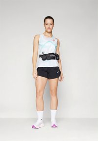 Jooksuriietus, mis sisaldab helesinist topi geomeetriliste mustritega, musti lühikesi pükse ja musta vöökotti, mida täiustavad valged sokid ja roosad jalanõud.