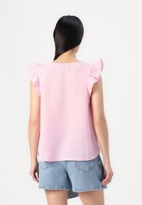 Top senza maniche rosa con dettagli arricciati sulle spalle, realizzato in un tessuto leggero. La parte posteriore presenta un collo arrotondato e una vestibilità comoda.