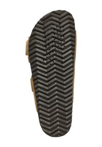 Zwarte rubberen zool met een zigzag profiel, voorzien van cirkelvormige ventilatiegaten en een lichtbruine suede bovenrand.