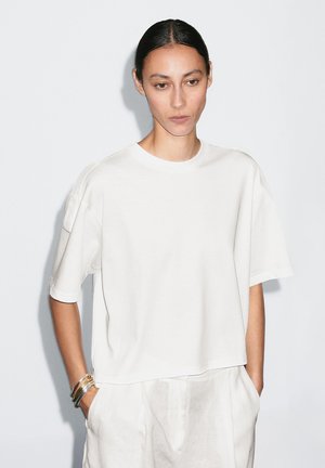 Witte katoenen t-shirt met korte mouwen, een ronde halslijn en een relaxte pasvorm. Opvallend detail: subtiele schouderaccenten.