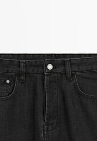 Jeans in denim nero con chiusura a bottone e cerniera, caratterizzati da un classico design a cinque tasche e dettagli di cucitura discreti.