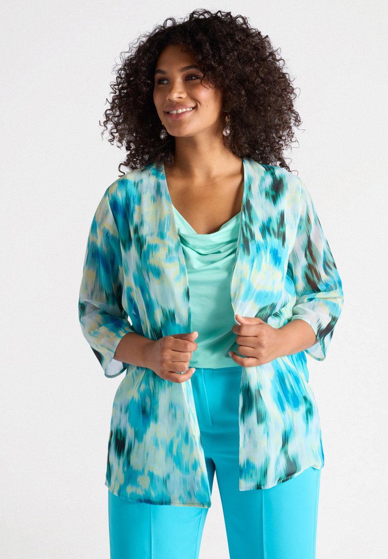 Lichte, semi-doorzichtige kimono met een levendig blauw en groen abstract patroon; gecombineerd met een top met col en bijpassende blauwe broek.