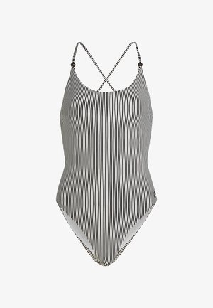 Gestreepte tankini in zwart-wit, met dunne kruislings bevestigde banden en een hoge beenuitsnede. Glad materiaal, geen versieringen.