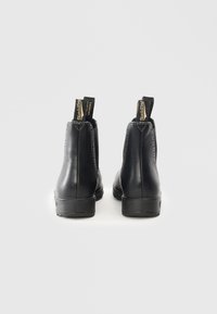 Bottines Chelsea en cuir noir avec panneaux élastiques sur les côtés, coutures contrastantes, languettes de tirage et semelle robuste et texturée.