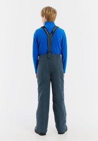 Een blauwe longsleeve shirt gecombineerd met donkergrijze sneeuwbroeken met verstelbare bandjes en een gladde textuur, ontworpen voor winteractiviteiten.