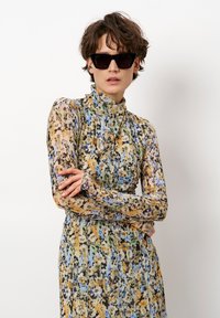 Langmouwen jurk met hoge hals, gemaakt van een lichtgewicht, gemarmerde stof in gele, blauwe en zwarte tinten. Beschikt over een geplooide rok en een slim fit.