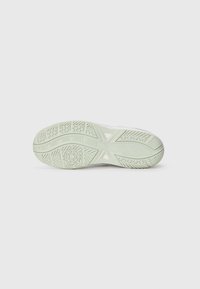 Semelle d'une chaussure en vert clair avec un motif texturé, comprenant des designs circulaires et linéaires. Non traçante avec le logo de la marque visible.