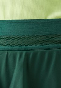 Groene sportbroekjes met een gestructureerde tailleband met mesh-details. De stof heeft een gladde afwerking en is lichtgewicht voor comfort.
