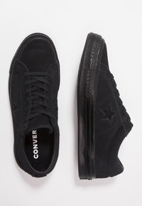 Zapatillas de ante negro con diseño de tipo bajo, suela de goma texturizada, cierre con cordones y acento del logo de estrella en el lateral.