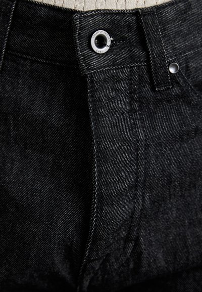 Černé džíny z denimu s hladkou texturou, s kovovým zapínáním na knoflíky a jemnými švy podél pasu a kapes.