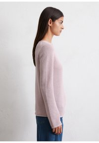 Jasnoróżowy sweter z dzianiny o długich rękawach, okrągłym dekolcie i teksturowanym splotem, w połączeniu z niebieskimi dżinsami. Prosty, casualowy design.