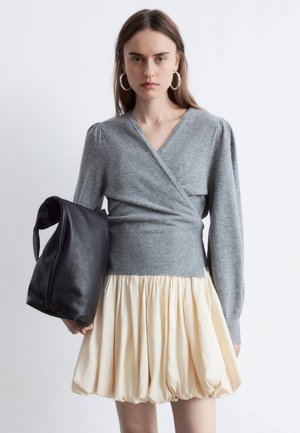 Gray wrap sweater with long sleeves, paired with a lightweight cream puff skirt. Black leather slouchy bag with a curved handle.