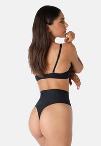 Set di bikini nero con reggiseno a chiusura posteriore e spalline regolabili, pantaloni a vita alta. Texture morbida e design minimalista.