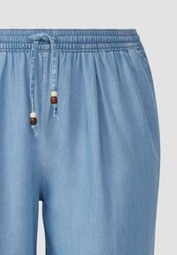 Pantalon léger en tissu bleu clair avec une taille élastique, fermeture à cordon et accents en perles en bois.