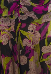 Floral fabric with large beige, pink, and green flowers on a black background, showing gathered and folded texture.
