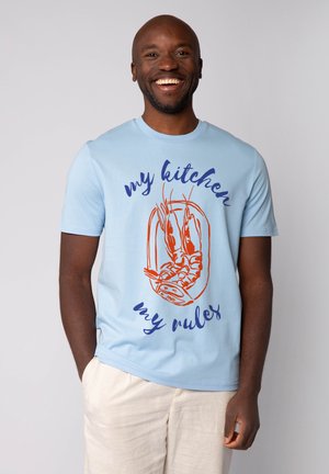 Light blue cotton t-shirt featuring orange lobster graphic and blue text reading "my kitchen my rules." Short sleeves, round neckline.