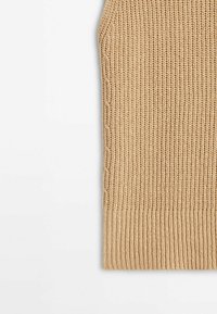 Tissu tricoté beige avec ourlet côtelé et détail de motif torsadé sur fond blanc plat.