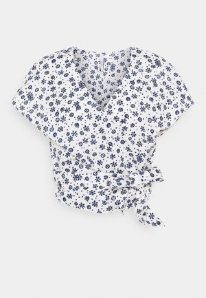 Valkoinen kietaisupusero, jossa lyhyet hihat, tummansininen kukka- ja pilkkukuvio, V-pääntie ja sivulta solmittava vyö.