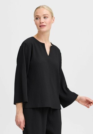 Black ribbed long-sleeve top with a V-neck, featuring a relaxed fit and subtle texture. The fabric has vertical stripes and a smooth finish.