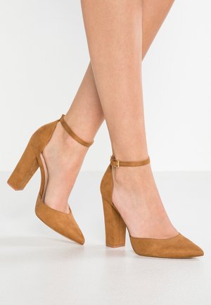 Brown suede high-heeled shoes with a pointed toe and ankle strap, featuring a block heel and smooth texture.
