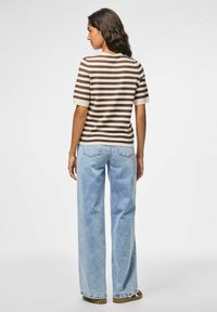Bruine en crème gestreepte t-shirt met korte mouwen, gecombineerd met lichtblauwe wijde jeans. Soepele textuur en ontspannen pasvorm met details van achterzakken.
