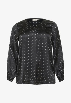 Blouse en satin noir avec de longues manches ballon, présentant un col en V et un motif à pois beige clair. Détail de pli central à l'avant.