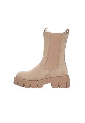 Bottine en suède beige avec des panneaux latéraux élastiques, une semelle épaisse et des languettes au dos. Texture lisse avec des coutures renforcées.
