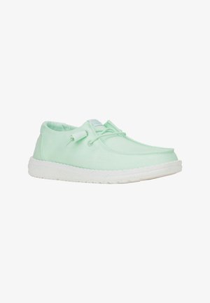 Chaussure en tissu vert clair avec un bout arrondi, un lacet et une semelle en caoutchouc blanche. Texture lisse avec des détails de couture subtils.