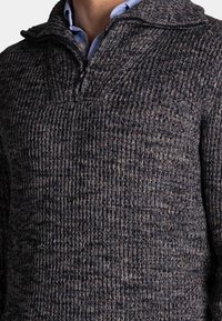 Gebreide trui met een hoge kraag, featuring een donkerblauw en grijs kleurenschema. Gelaagd stof met een subtiel diagonale patroon en een kwart rits.