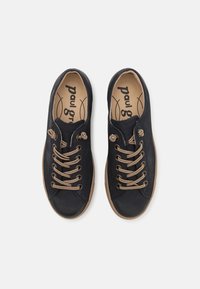 Svarta canvas-sneakers med bruna snören, rund tå, gummisulor och logotyp på innersulan. Har två öglor nära tån för extra detalj.