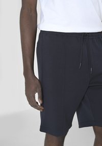 Pantaloni sportivi blu navy realizzati in morbido tessuto elasticizzato con vita elasticizzata e cordoncino. Include tasche laterali.
