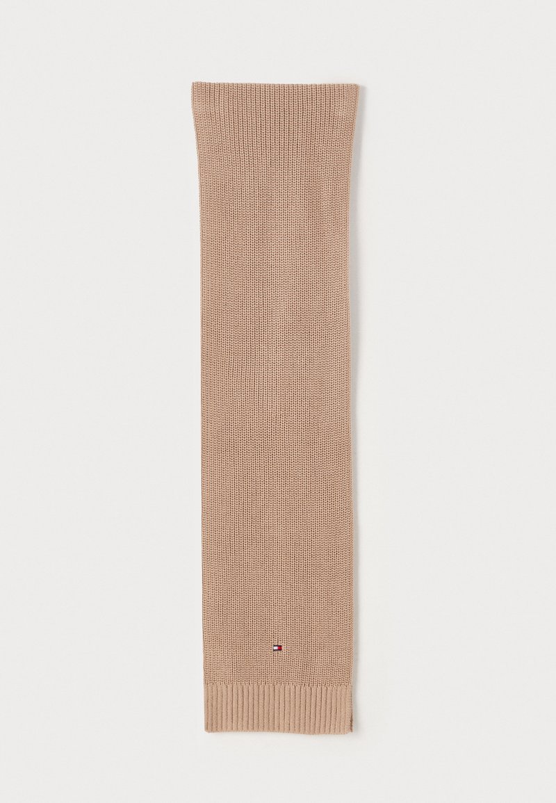 Calza in maglia beige con estremità a costine, dotata di una piccola etichetta con logo vicino al fondo. Texture morbida e forma allungata per garantire calore.
