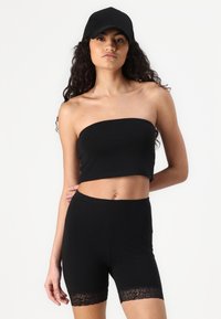 Black strapless crop top with matching high-waisted shorts featuring lace accents at the hem. Made from a smooth, stretchy fabric.