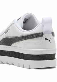 Λευκό αθλητικό παπούτσι με γκρίζες σουέτ λεπτομέρειες, υφασμάτινη μαύρη σόλα και λευκή καουτσούκ εξωτερική σόλα. Διαθέτει λογότυπο PUMA και μια θηλιά στο τακούνι.