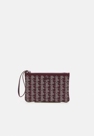 Rechthoekige wijnrode polstasje met wit geometrisch patroon, ritssluiting en een lusvormig handvat aan de linkerkant.