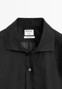 Schwarzes Leinenhemd mit spitzem Kragen, einreihigem Knopfverschluss und innerem Etikett mit der Aufschrift "Massimo Dutti Studio, Hergestellt in Spanien."