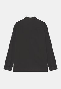 Black long-sleeve shirt with a collared neckline, buttoned cuffs, and a patch on the left sleeve. Smooth texture and tailored fit.