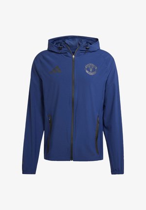Plava zip-jakna s kapuljačom, s crnim naglascima i logom Manchester Uniteda na prsima. Izrađena od prozračnog materijala s bočnim džepovima.