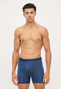 Tumši zili bokseršorti ar gludu tekstūru un elastīgu jostasvietu, uz kuras ir tumši zils "BJÖRN BORG" logo. Forma pieguļošs dizains.
