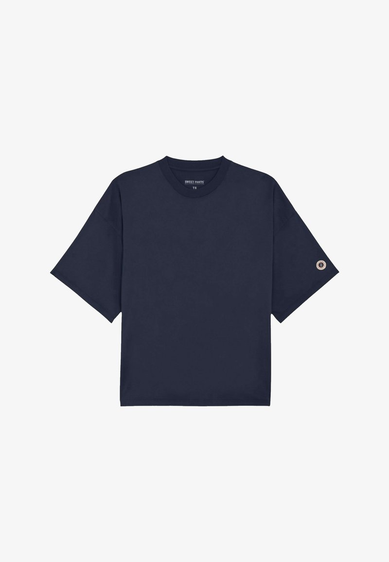 T-shirt à manches courtes surdimensionné bleu marine avec col rond et petit logo circulaire sur la manche gauche.