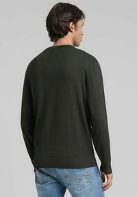 Donkergroene, gebreide trui met een ronde hals en lange mouwen. Heeft een geribbelde zoom en manchetten, met een gladde textuur.