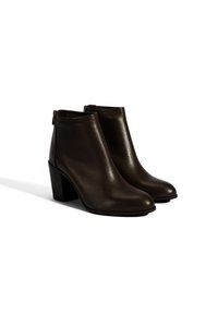 Bruine leren enkelboots met een gladde afwerking, een spits toelopende neus en een grove hak. Voorzien van een rits aan de achterkant voor eenvoudig aan- en uittrekken.