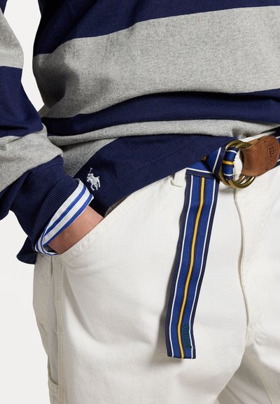 Navy and grey striped long-sleeve shirt, with white undershirt cuffs. White pants accentuated by a blue, yellow, and green striped belt.