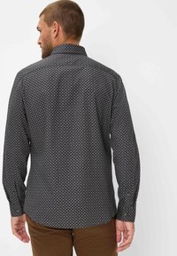Schwarzes Hemd mit Knöpfen und einem kleinen blauen Blumendruck, mit Kragen, langen Ärmeln und abgerundetem Saum. Aus leichtem Stoff gefertigt.