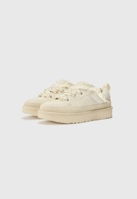 Beige sportschoenen met een mix van suède en textiel bovenwerk, dikke rubberen zool en gestructureerde veters met een patroonontwerp op de tong.