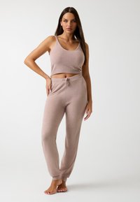 Top corto de punto color rosa claro con tirantes anchos y pantalones jogger a juego que se ponen fácilmente, con una cinturilla ajustable y puños acanalados.
